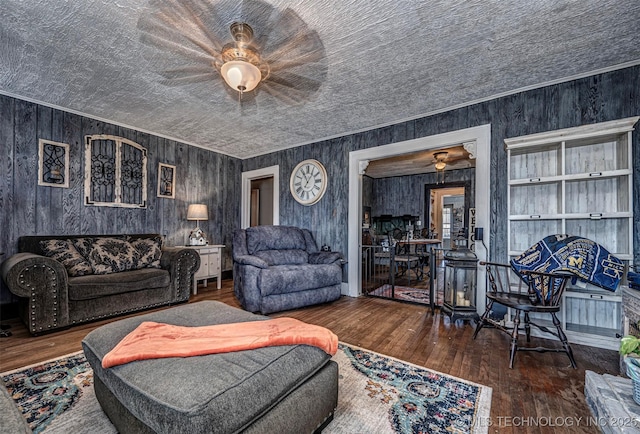 living room featuring dark hardwood / wood-style flooring, ceiling fan, and wood walls