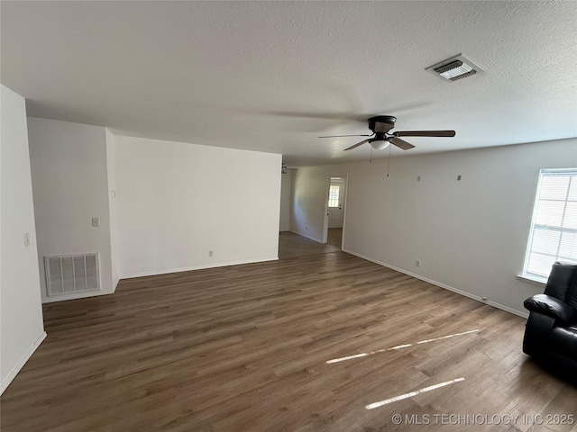 unfurnished living room with a textured ceiling, ceiling fan, and dark wood-type flooring