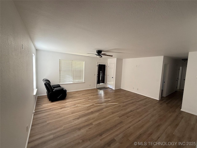 unfurnished living room featuring ceiling fan, dark hardwood / wood-style flooring, and a textured ceiling