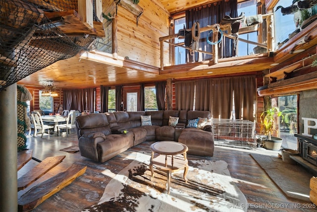 living room with hardwood / wood-style floors, an inviting chandelier, wooden ceiling, a high ceiling, and wood walls