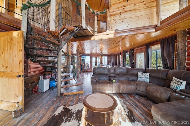 living room featuring wood walls, dark wood-type flooring, and high vaulted ceiling