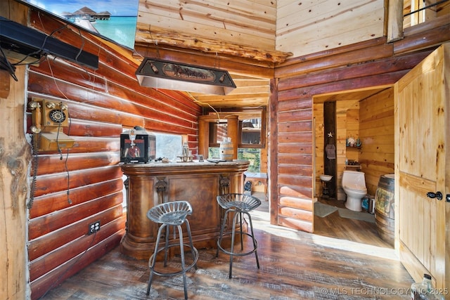 bar with log walls and dark hardwood / wood-style floors