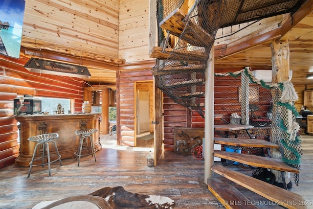 interior space with log walls, wood-type flooring, and a high ceiling