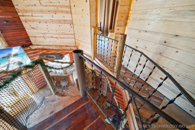 staircase with wooden walls and hardwood / wood-style flooring