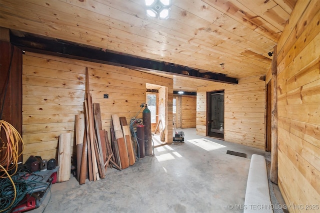 interior space with wooden walls, concrete floors, and wooden ceiling