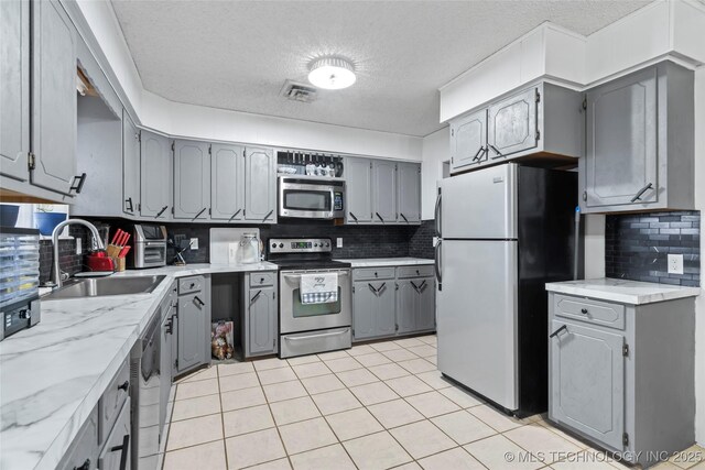 kitchen with tasteful backsplash, sink, stainless steel appliances, and a textured ceiling