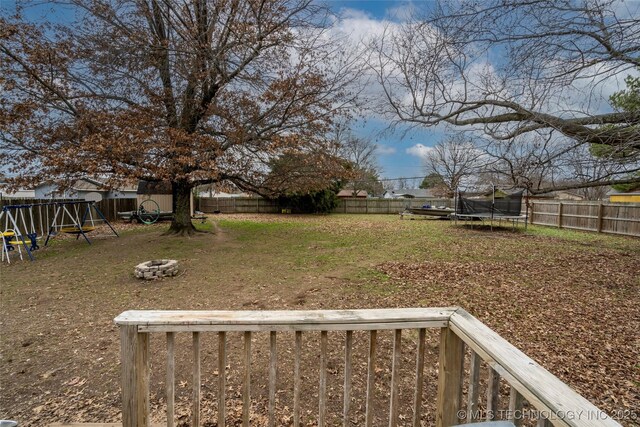 view of yard with a playground, a fire pit, and a trampoline