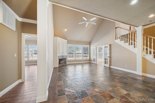 unfurnished living room with a tile fireplace, ceiling fan, high vaulted ceiling, and a healthy amount of sunlight