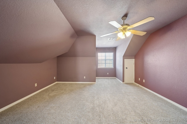 additional living space with lofted ceiling, ceiling fan, light carpet, and a textured ceiling