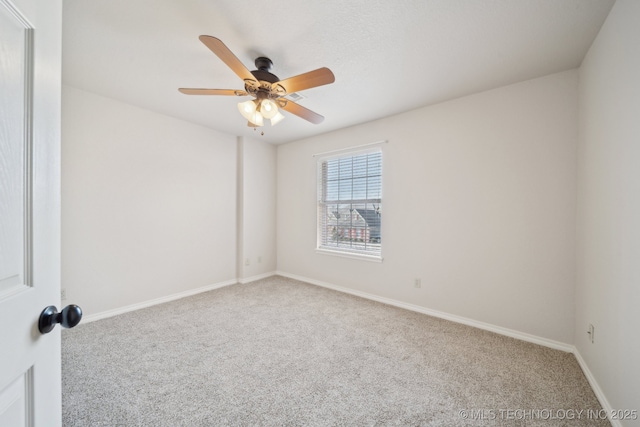 carpeted spare room with a ceiling fan and baseboards