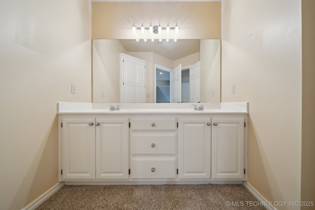 full bathroom with double vanity, a sink, carpet floors, and baseboards