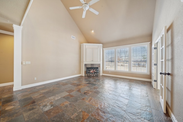 unfurnished living room featuring visible vents, baseboards, stone tile flooring, and high vaulted ceiling