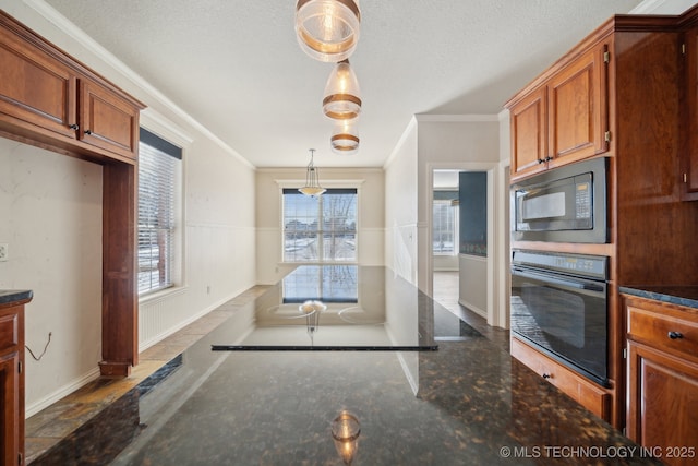 kitchen with decorative light fixtures, crown molding, dark stone counters, and black appliances