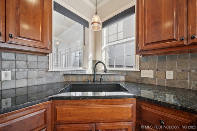 kitchen with backsplash, decorative light fixtures, dark stone counters, and sink