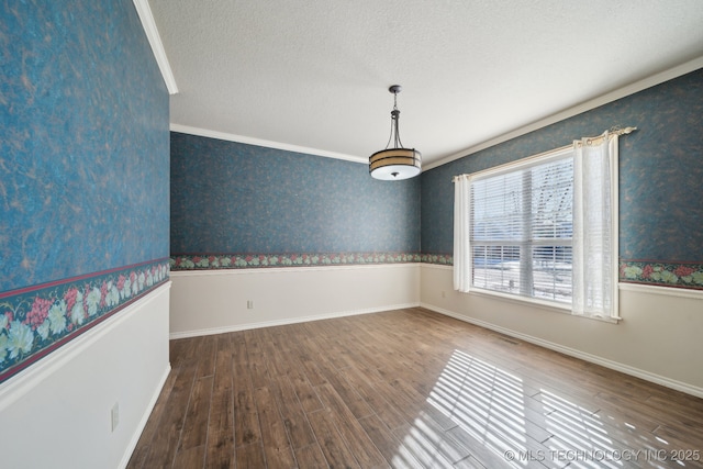 empty room with a textured ceiling, wood-type flooring, and crown molding