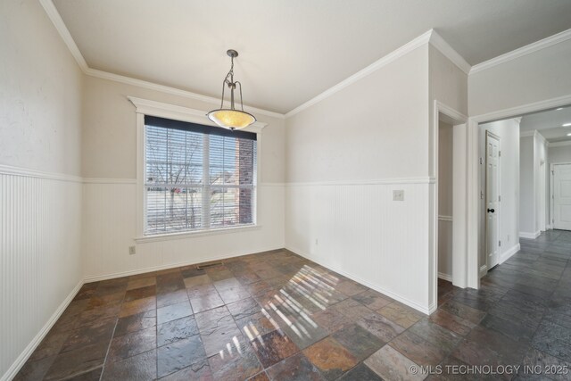 unfurnished dining area featuring wainscoting, baseboards, stone tile flooring, and crown molding