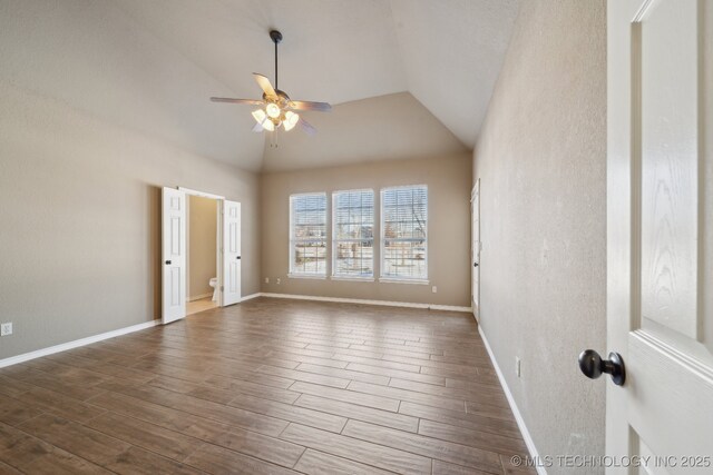 unfurnished room with baseboards, vaulted ceiling, dark wood-style floors, and ceiling fan
