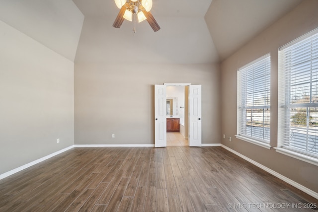 empty room with dark wood-style flooring, baseboards, visible vents, a ceiling fan, and high vaulted ceiling