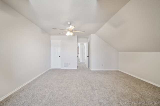 bonus room featuring vaulted ceiling, baseboards, visible vents, light colored carpet, and ceiling fan