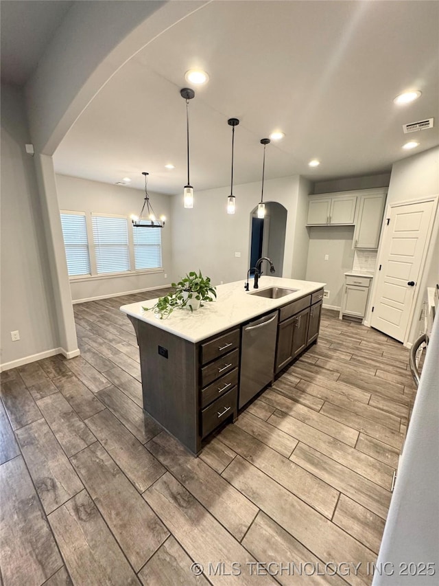 kitchen featuring dishwasher, sink, an island with sink, decorative light fixtures, and a chandelier