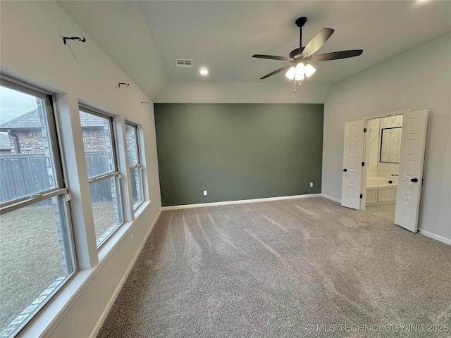 unfurnished bedroom featuring carpet, ceiling fan, multiple windows, and vaulted ceiling