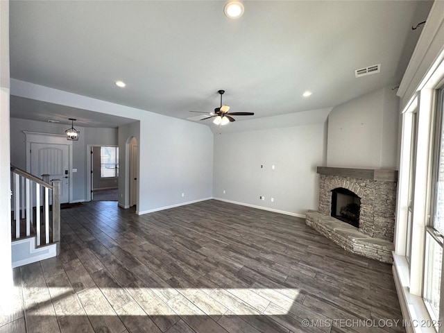 unfurnished living room featuring a fireplace, ceiling fan with notable chandelier, vaulted ceiling, and dark wood-type flooring