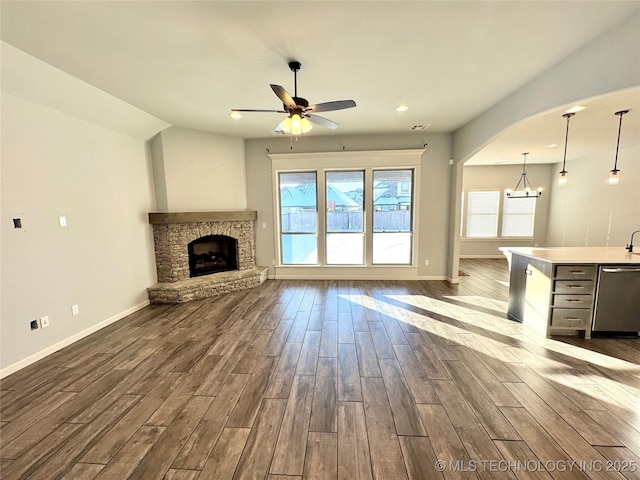 unfurnished living room with a fireplace and ceiling fan with notable chandelier