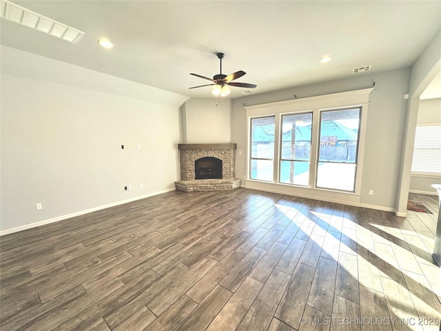 unfurnished living room with a stone fireplace, ceiling fan, and vaulted ceiling