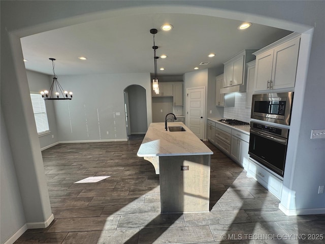 kitchen with an inviting chandelier, sink, an island with sink, appliances with stainless steel finishes, and decorative light fixtures