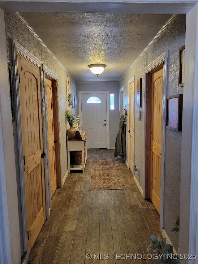 doorway with a textured ceiling, dark hardwood / wood-style floors, and crown molding