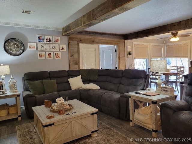 living room with beamed ceiling, a textured ceiling, ceiling fan, and dark wood-type flooring