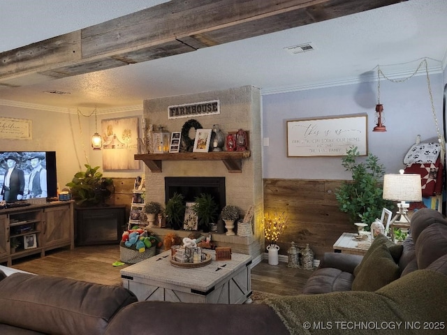 living room featuring wood-type flooring, a large fireplace, crown molding, and wooden walls