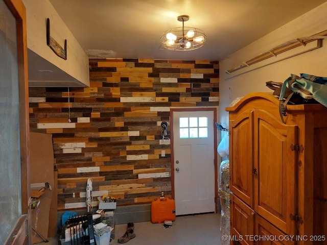 entryway with wood walls and a chandelier