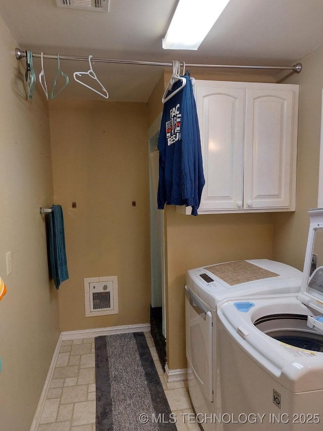 clothes washing area featuring cabinets and washing machine and clothes dryer