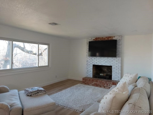 living room featuring hardwood / wood-style floors, a textured ceiling, and a brick fireplace