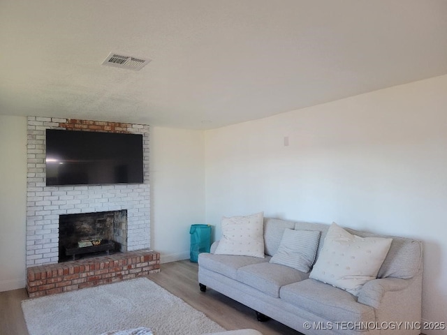 living room with light hardwood / wood-style floors and a brick fireplace