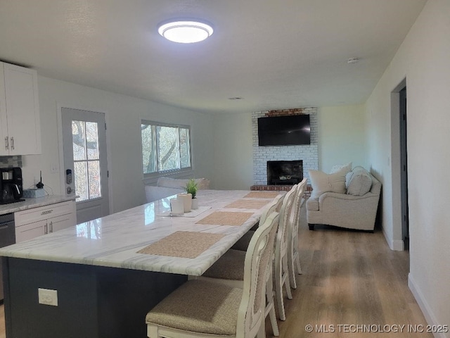 dining room featuring hardwood / wood-style floors and a brick fireplace