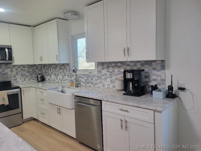 kitchen with appliances with stainless steel finishes, tasteful backsplash, and white cabinetry