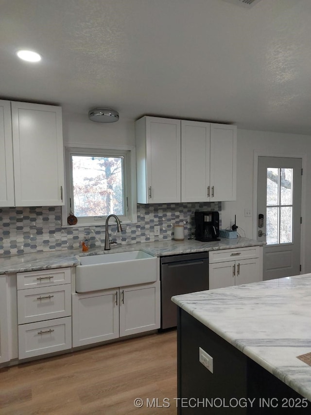 kitchen featuring light stone countertops, sink, dishwasher, light hardwood / wood-style floors, and white cabinetry