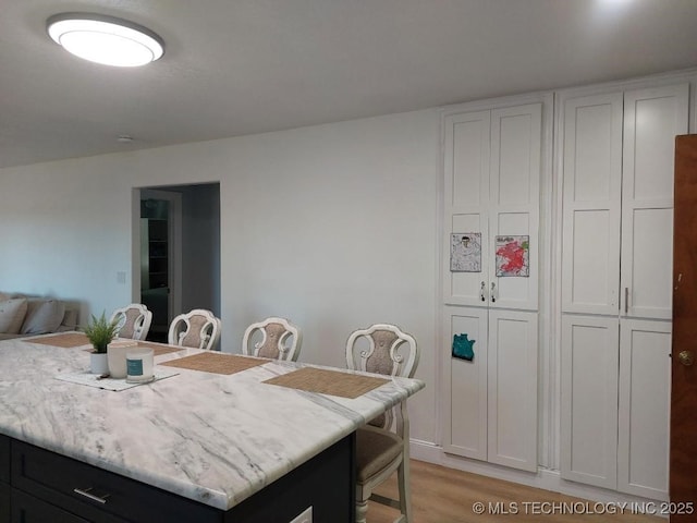 kitchen with white cabinets, a kitchen island, and light wood-type flooring