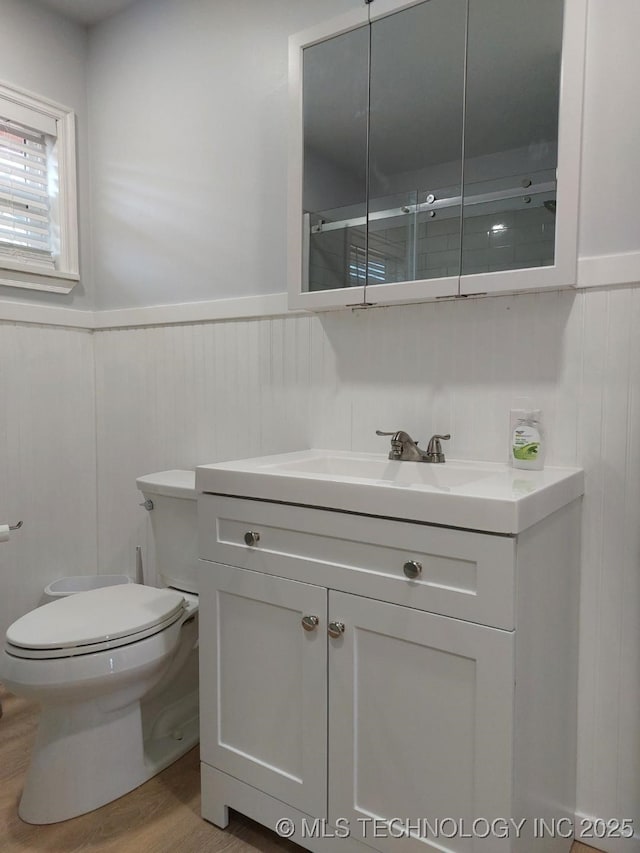 bathroom featuring hardwood / wood-style flooring, vanity, toilet, and an enclosed shower