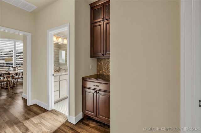 bar with decorative backsplash, dark brown cabinets, and dark hardwood / wood-style floors