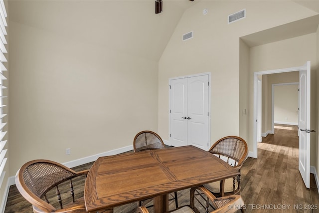 dining room with high vaulted ceiling and dark hardwood / wood-style floors