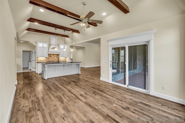 unfurnished living room featuring ceiling fan, lofted ceiling with beams, light hardwood / wood-style floors, and sink