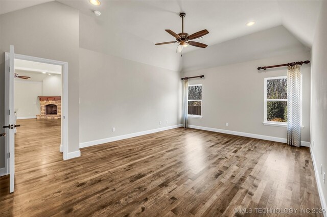 spare room featuring a fireplace, hardwood / wood-style floors, ceiling fan, and lofted ceiling