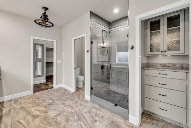 bathroom featuring toilet, an enclosed shower, and vanity