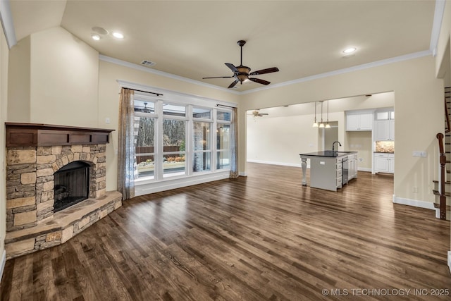 unfurnished living room with ceiling fan, crown molding, sink, a fireplace, and dark hardwood / wood-style floors