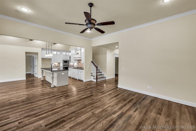 unfurnished living room with dark hardwood / wood-style flooring, ceiling fan, ornamental molding, and sink