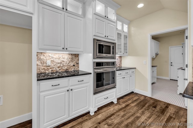 kitchen featuring appliances with stainless steel finishes, backsplash, white cabinetry, and lofted ceiling