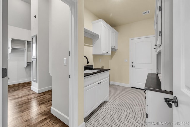 kitchen with white cabinets, light wood-type flooring, and sink